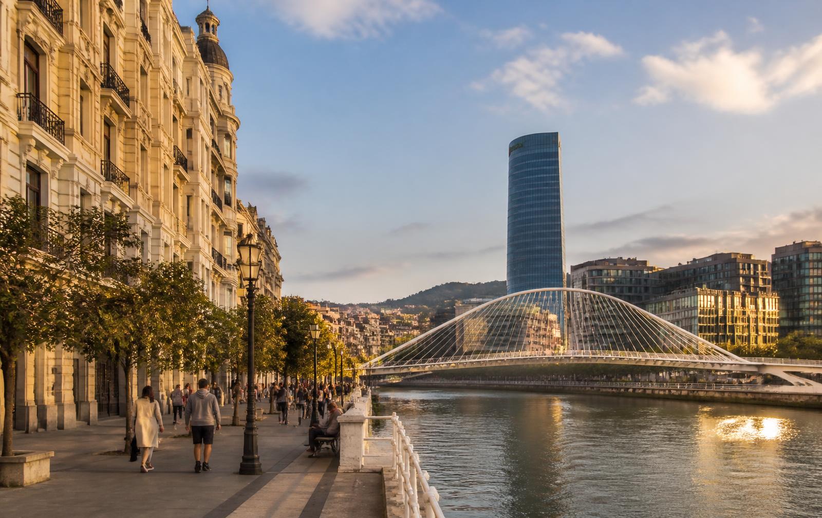 Ría de Bilbao con la pasarela Zubizuri y edificios de viviendas al atardecer